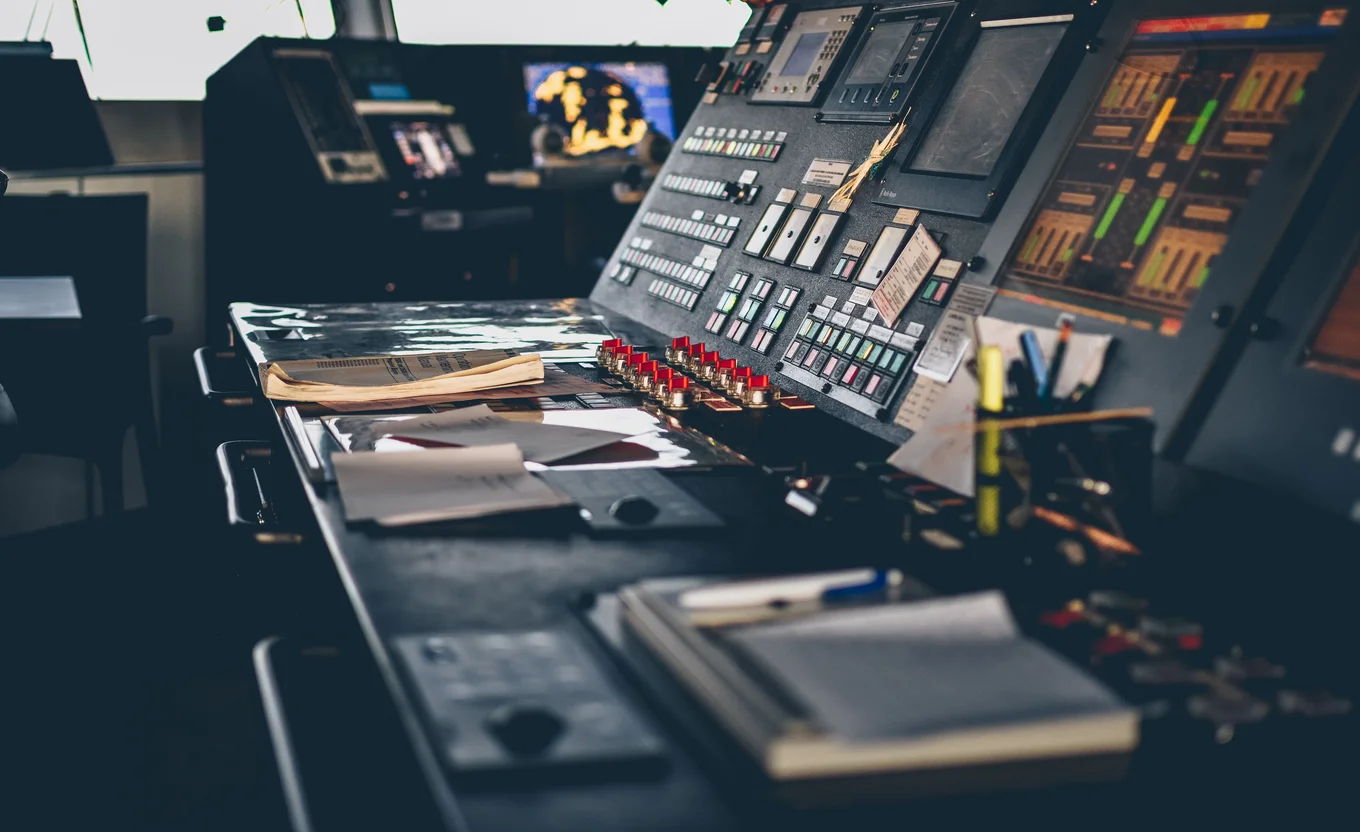 Control panel with screens, buttons, papers, pens.